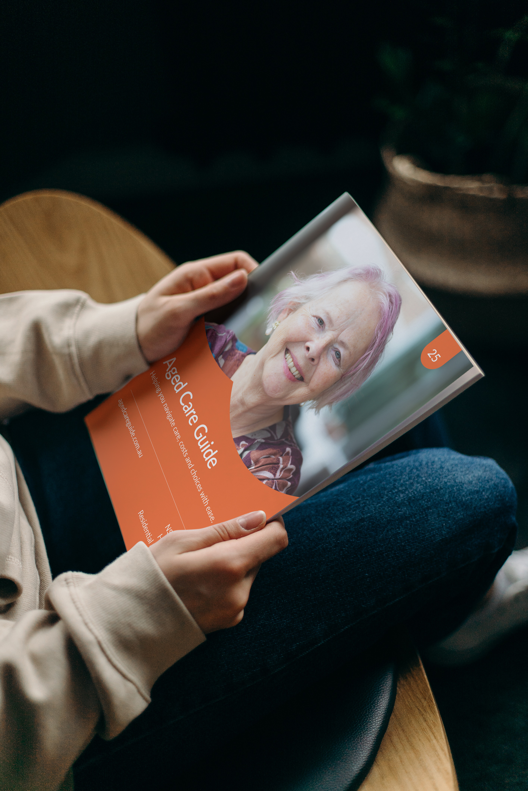 A person's hands holding an Aged Care Guide with a portrait image of an older woman on the cover.